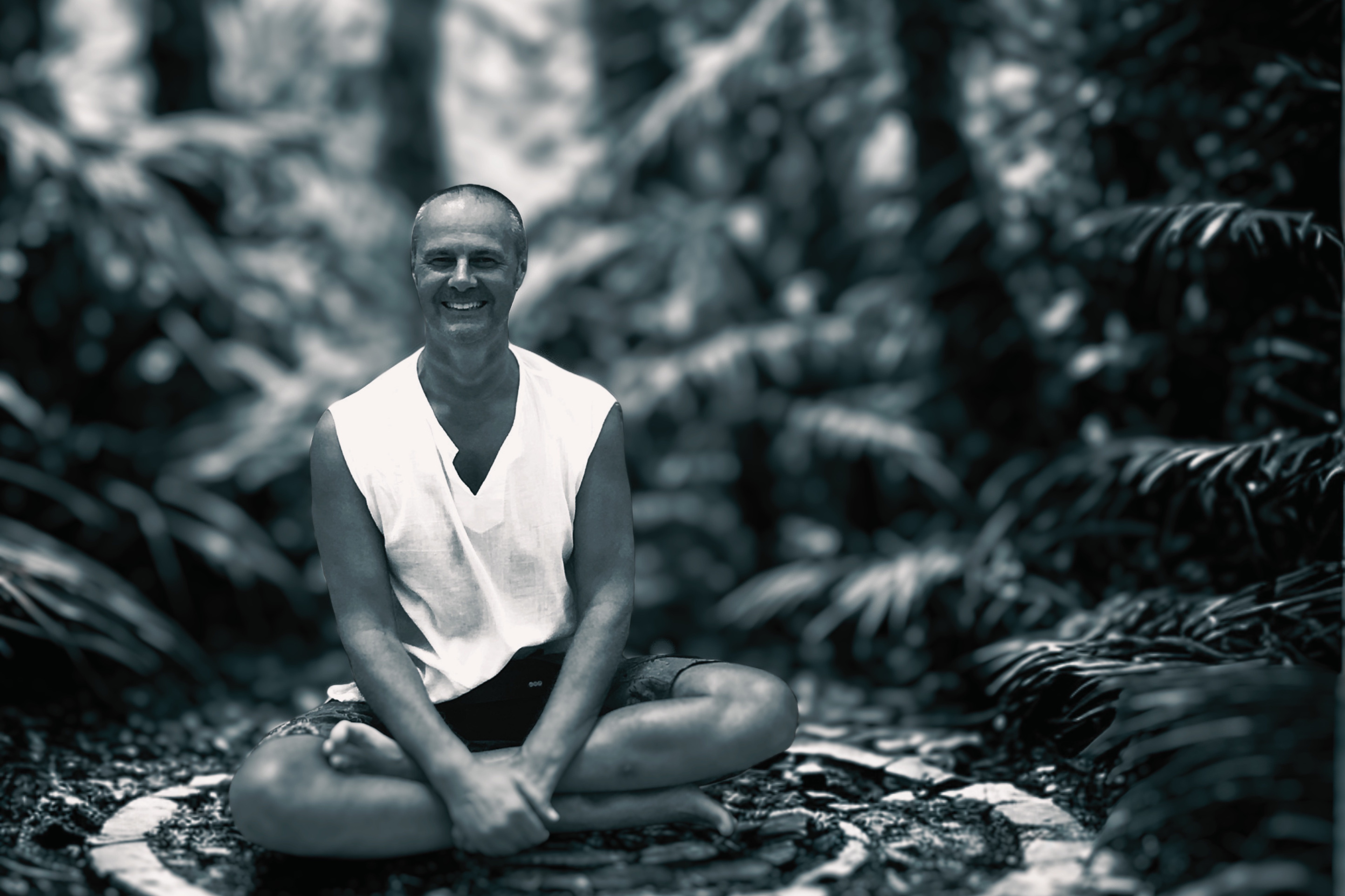 Bruce Mackay seated cross-legged among jungle ferns