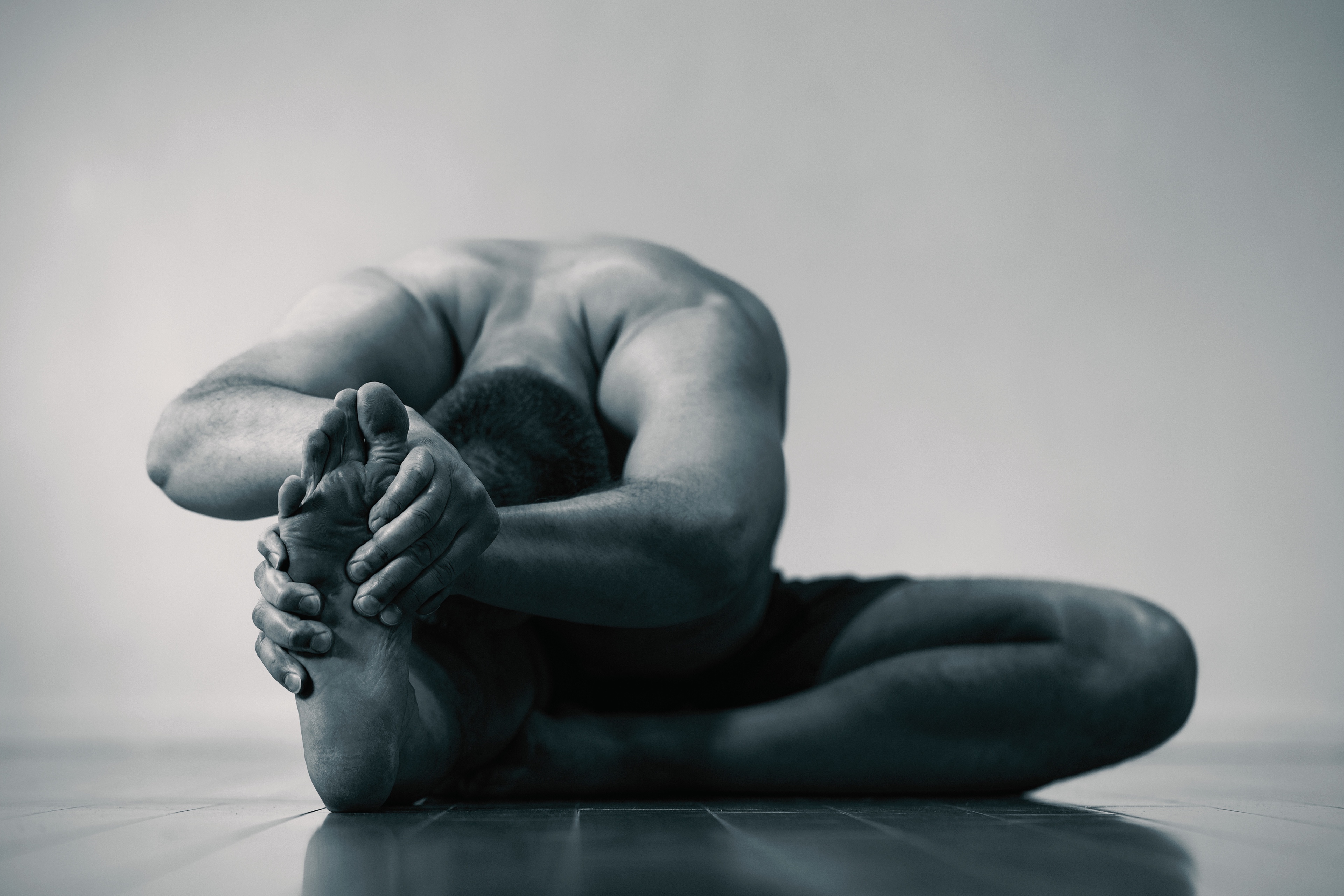 Bruce Mackay in a deep seated forward fold, duotone