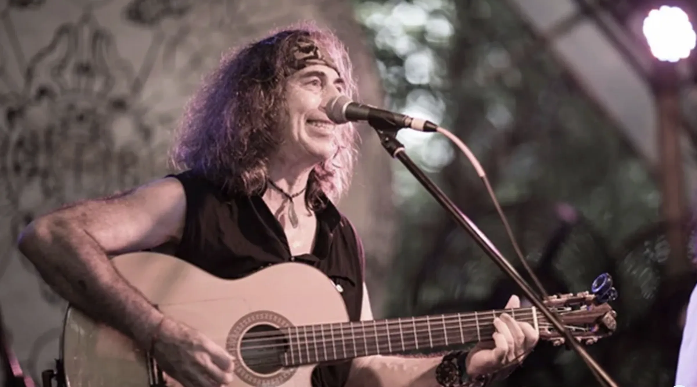 Danny Paradise singing and playing acoustic guitar on stage
